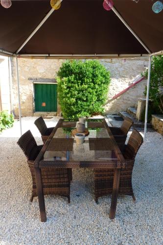 une table en verre avec des chaises et une plante sur la terrasse dans l'établissement Les Gîtes de l'Orta, à Saint-Jean-dʼEyraud