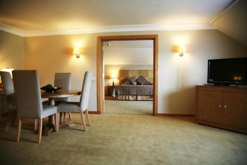 a living room with a table and a television and a bedroom at Regency Park Hotel, Health Club & Spa in Newbury