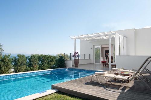 a swimming pool with a deck and chairs next to it at Kappa Resort in Paliouri