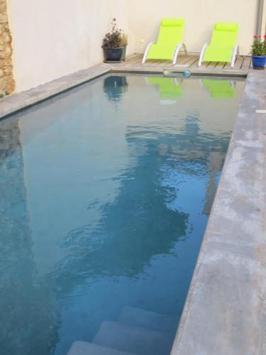 - une piscine avec 2 chaises vertes dans l'établissement Gite Les Enfantines, à Bédoin