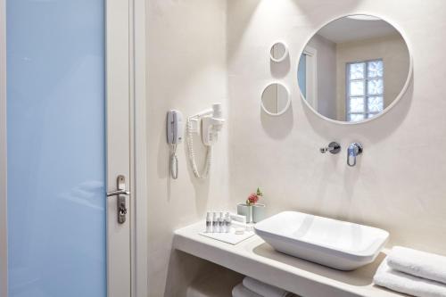 a bathroom with a sink, mirror and bath tub at Santo Miramare Beach Resort in Perivolos