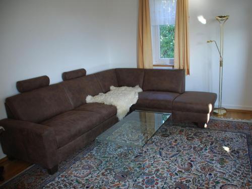 ein Wohnzimmer mit einem braunen Sofa und einem Glastisch in der Unterkunft Blum Ferienwohnung in Konstanz