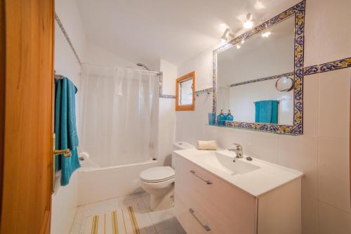 a bathroom with a sink and a toilet and a mirror at Can Cusina in Es Llombards