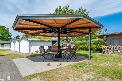 un patio con mesa y sillas bajo una sombrilla de madera en Pension Middel, en Binz