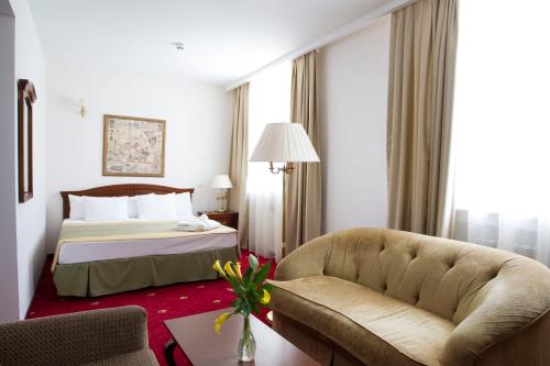 Habitación de hotel con cama y sofá en Atyrau Dastan Hotel en Atyraū