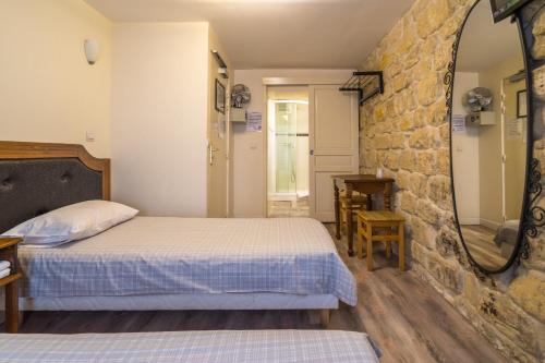um quarto com uma cama e uma parede de pedra em Grand Hôtel de Clermont em Paris