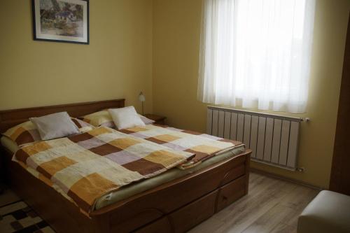 a bedroom with a bed with a blanket and a window at Bodó Park Apartment in Hévíz