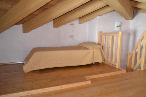 a bed in a room with wooden floors and beams at Casa Vacanza La Rocca in Chiesa in Valmalenco