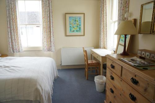 a bedroom with a bed and a desk and window at Minton House in Colyton