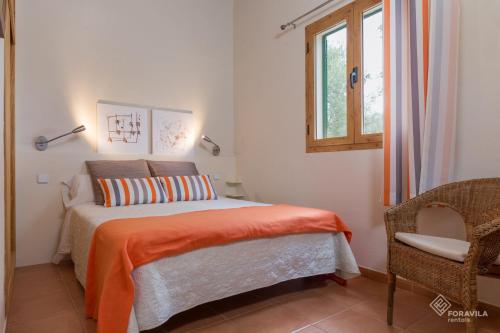 - une chambre avec un lit doté d'une couverture orange et d'une fenêtre dans l'établissement Son Fornes, à Algaida