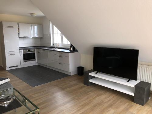 a living room with a flat screen tv and a kitchen at Ferienwohnung "Kranich" im Ferien-Resort Rügen in Sagard