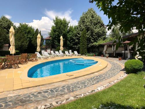 a swimming pool with chairs and umbrellas in a yard at Olymp Hotel in Bansko