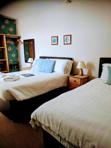 a bedroom with two beds and a night stand with two lamps at Craigwell in Morecambe