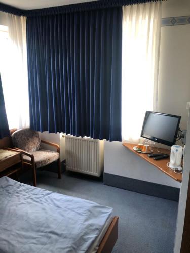 a hotel room with a bed and a desk with a television at Hotel Mylos in Sittensen
