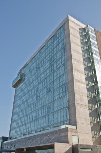 a tall building with glass windows on top of it at Casa Inn Premium Hotel Queretaro in Querétaro