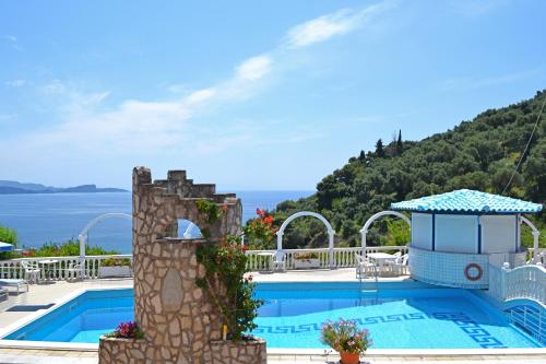 a pool at a resort with the ocean in the background at Dolphin Apartments 1 in Parga
