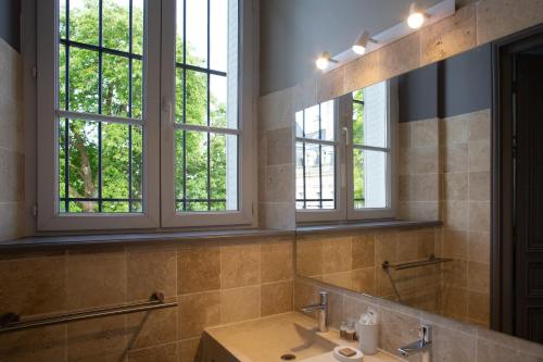 a bathroom with a sink and two windows at La Cave de l'Avenue de champagne in Épernay