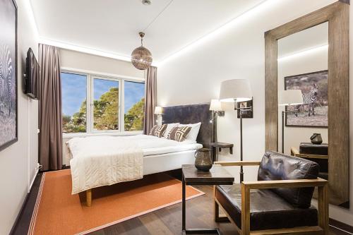 ein Schlafzimmer mit einem Bett, einem Stuhl und einem Fenster in der Unterkunft Dyreparken Safarihotell in Kristiansand