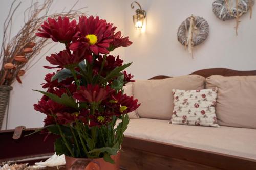a vase filled with red flowers in front of a couch at Kaminos Boutique Hotel in Symi