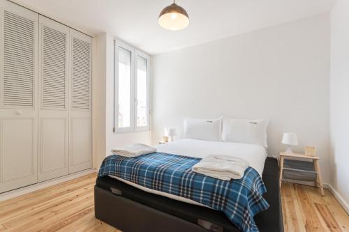 a white bedroom with a large bed and a window at FLH Príncipe Real Bright Apartment in Lisbon