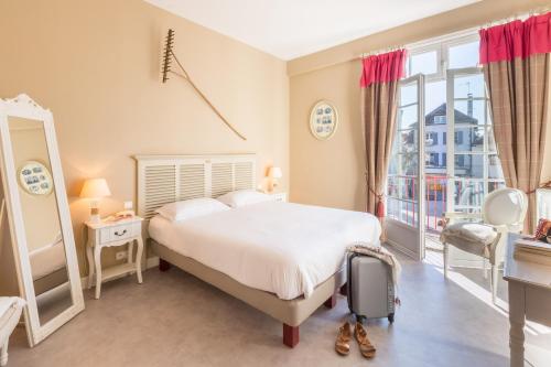 a bedroom with a bed and a large window at Logis Hôtel Le Beaulieu in Beaulieu-sur-Dordogne