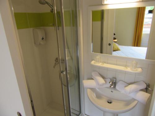 a bathroom with a sink and a shower with a mirror at Contact Hotel de France in Saintes