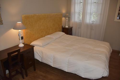 1 dormitorio con 1 cama blanca y mesita de noche con 2 lámparas en La Torre Rooms en San Quirico dʼOrcia