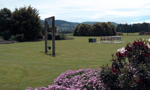 a park with a bench in a field with flowers at Longbourne Lodge Motel Mosgiel in Mosgiel