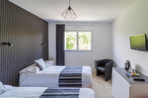 a hotel room with two beds and a television at Chambres du Bout du Monde in Landévennec
