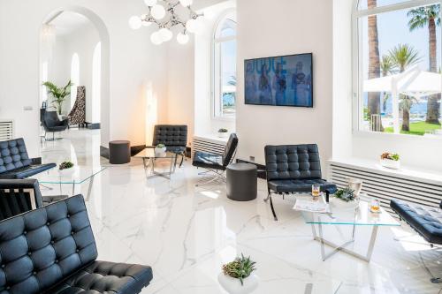 a lobby with black chairs and tables and windows at Miramare The Palace Resort in Sanremo
