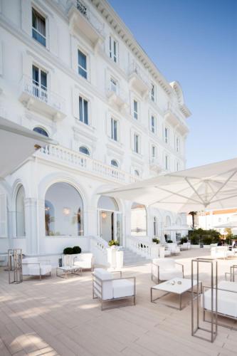 a large white building with tables and white chairs at Miramare The Palace Resort in Sanremo