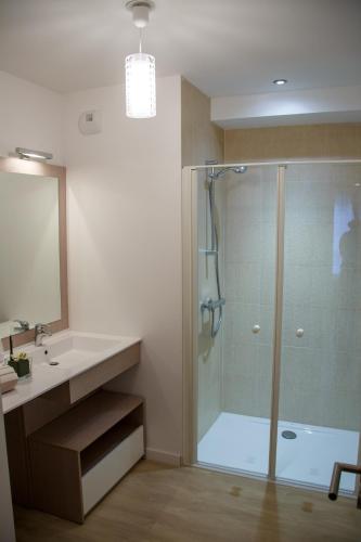 a bathroom with a glass shower and a sink at Domitys Le Pavillon de Diane in Thionville