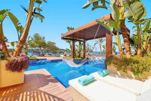 a resort pool with a hammock and palm trees at Iberostar Selection Jardín del Sol Suites - Adults Only in Santa Ponsa