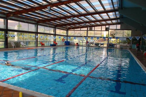 uma grande piscina com água azul num edifício em Nir David Country Lodge em Nir David