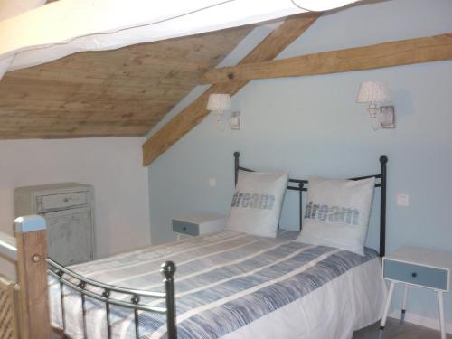 Un dormitorio con una cama con sábanas blancas y techos de madera. en Pèque-Lèbre, en Saint-Daunès
