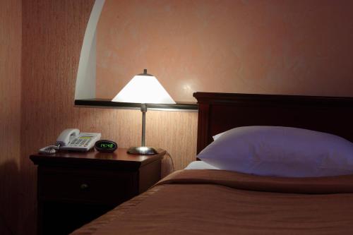 a bedroom with a bed with a lamp and a telephone at Victoria Hotel in Kharkiv