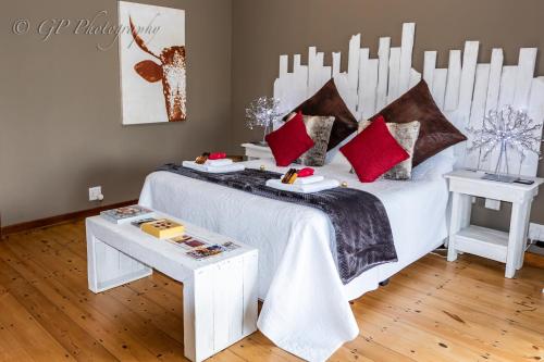 a bedroom with a white bed with red pillows at Laguna Lodge in Graskop