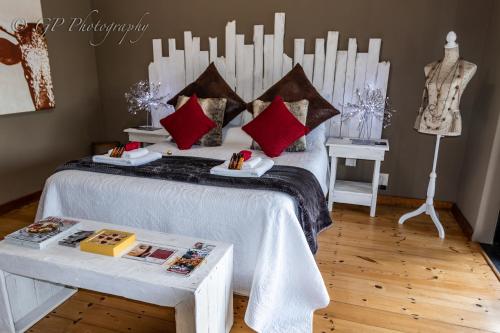 a bedroom with a white bed with red pillows at Laguna Lodge in Graskop