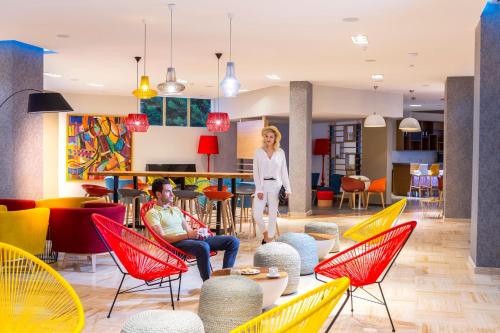 a woman standing in a lobby with colorful chairs at Leonardo Laura Beach & Splash Resort in Paphos City