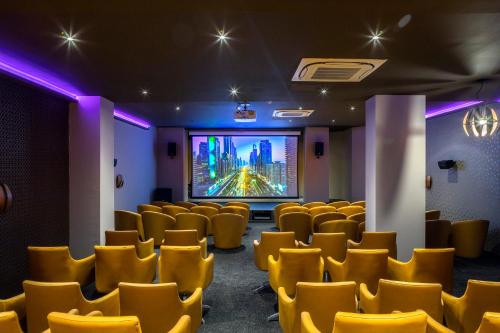 a cinema room with yellow chairs and a projection screen at Leonardo Laura Beach & Splash Resort in Paphos City