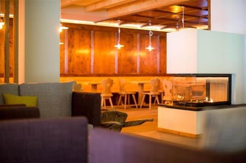 a living room with a fireplace and a table with chairs at Hotel La Baita in Folgaria