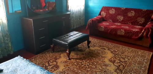 a living room with a red couch and a stool at Luka House in Akhaldaba