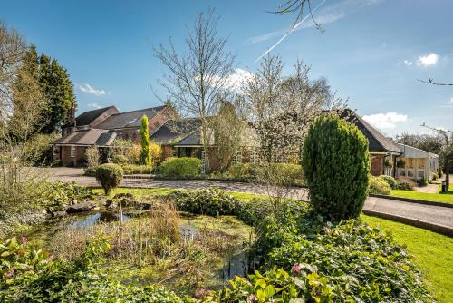 a garden with a pond in front of a house at Marston Farm Hotel in Sutton Coldfield