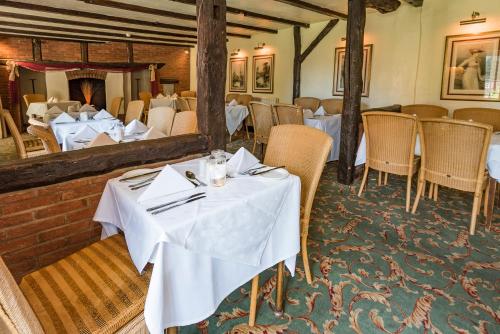 a restaurant with white tables and chairs and a mirror at Marston Farm Hotel in Sutton Coldfield