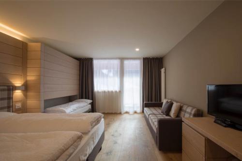 a hotel room with two beds and a flat screen tv at Hotel La Baita in Folgaria