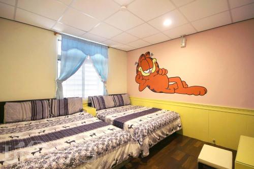 a bedroom with two beds and a cartoon monkey on the wall at Her Home Homestay in Green Island