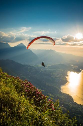 a person flying a parachute over a lake at Happy Inn Lodge in Interlaken