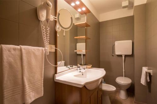 a bathroom with a sink and a toilet and a mirror at Hotel La Baita in Folgaria