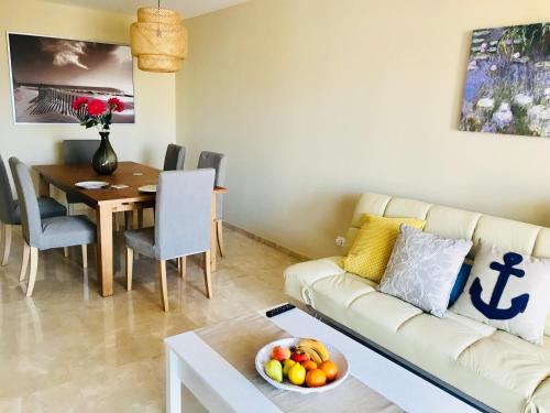 sala de estar con sofá y mesa con un bol de fruta en Alcaidesa Golf & Relax en Alcaidesa