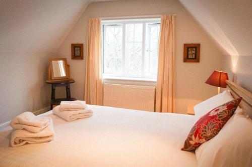 a bedroom with a bed with white sheets and a window at The Shoe Inn in Plaitford